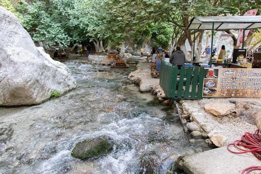 A stream with rocks, a coffee house, and people. 5