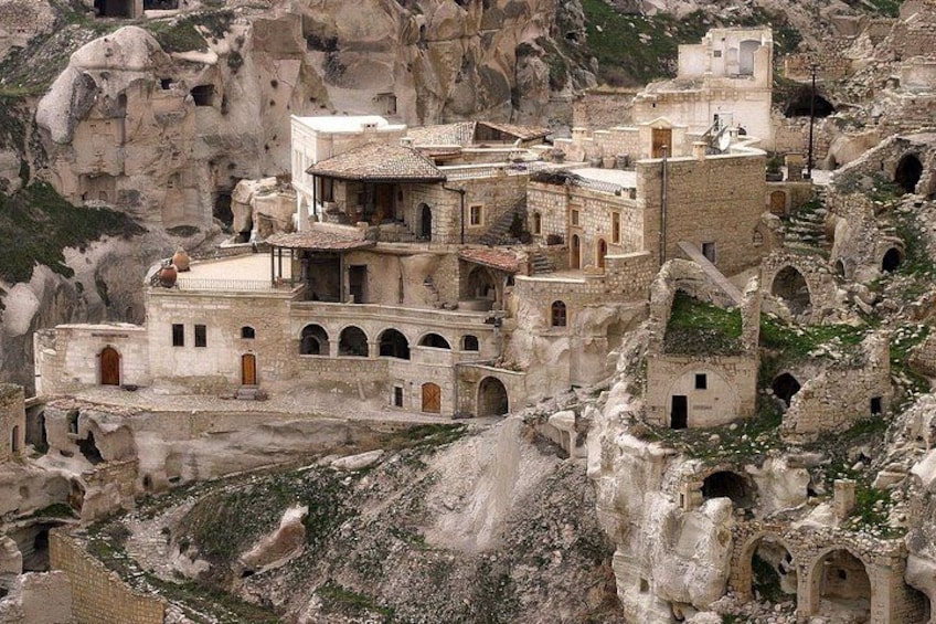 A village with traditional stone buildings nestled in a rocky landscape with numerous cave-like structures. 2
