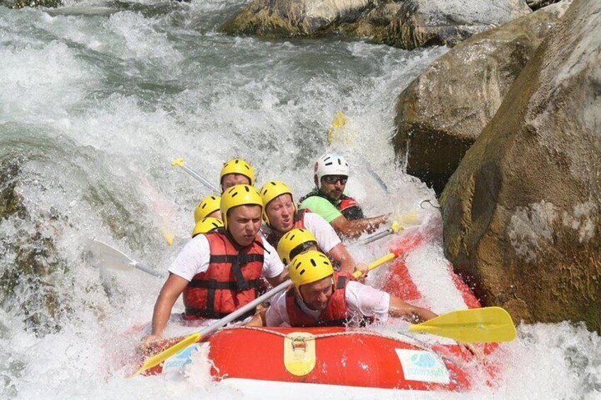 Un grupo de personas en una balsa roja navegando un río con rápidos. 1