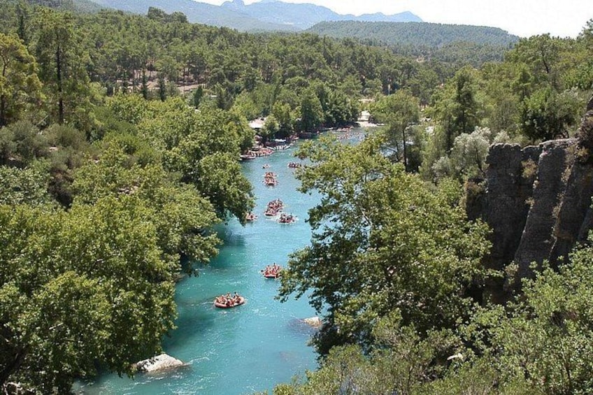 Un río rodeado de un denso bosque verde, con varias embarcaciones flotando sobre el agua. 5