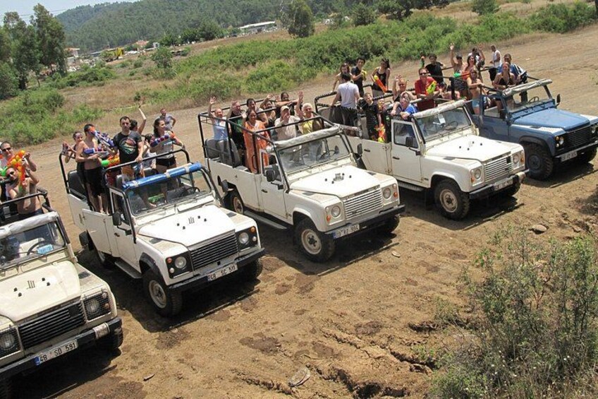 A group of people on a safari tour, riding in open-top safari vehicles. 4