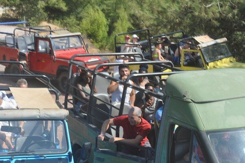 A group of people on a vehicle with a metal frame, surrounded by other vehicles. 3