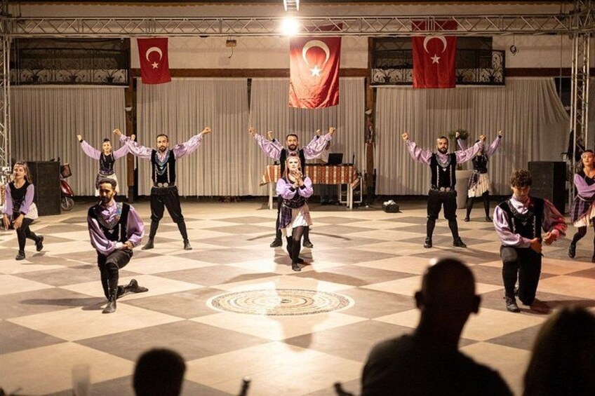 A group performing a dance on a checkered floor with flags in the background. 5