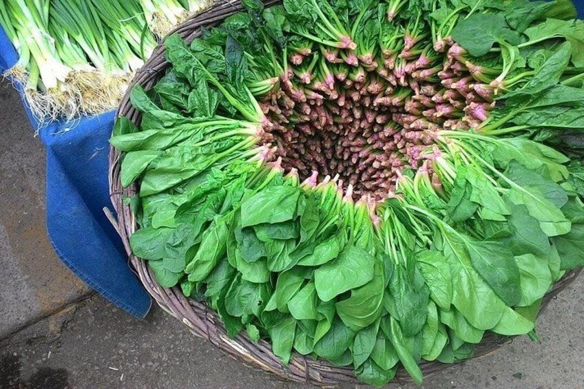 Un panier rempli de légumes-feuilles, avec un tissu bleu placé en dessous. 2