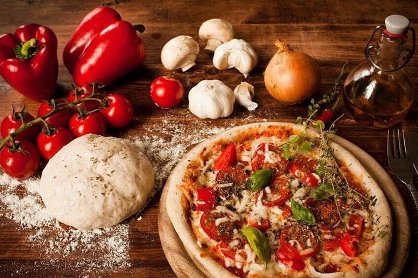 Une pizza garnie de divers ingrédients : un poivron entier, un oignon entier, une tête d’ail entière, une tomate entière, un poivron rouge entier, une feuille de basilic entière et une tête d’ail entière. 5