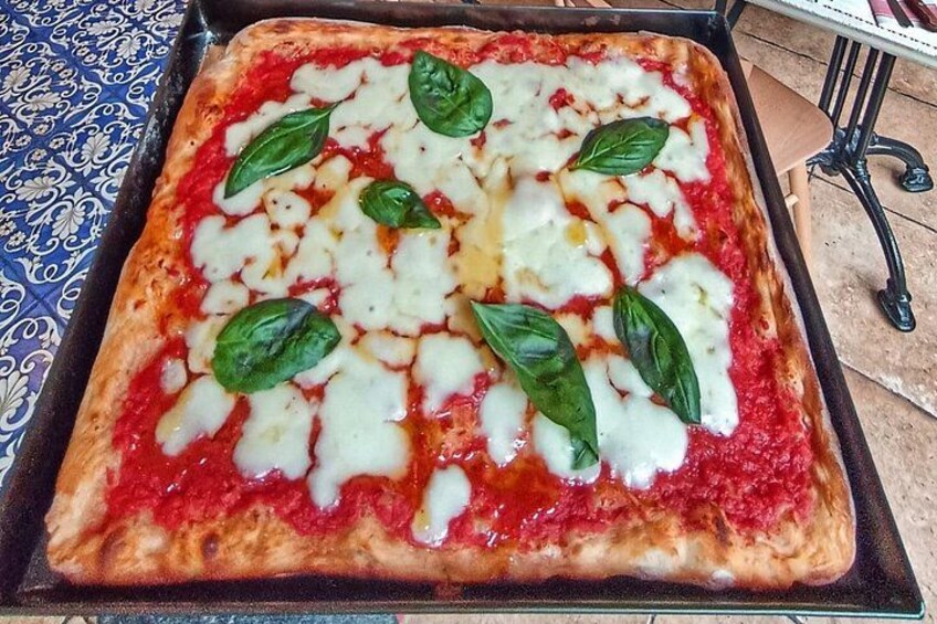 A pizza with cheese and basil leaves on a tray. 4