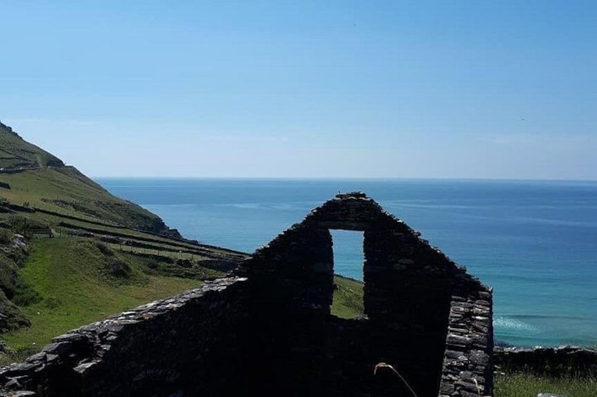 A coastal landscape with a ruined stone structure and a view of the sea. 5