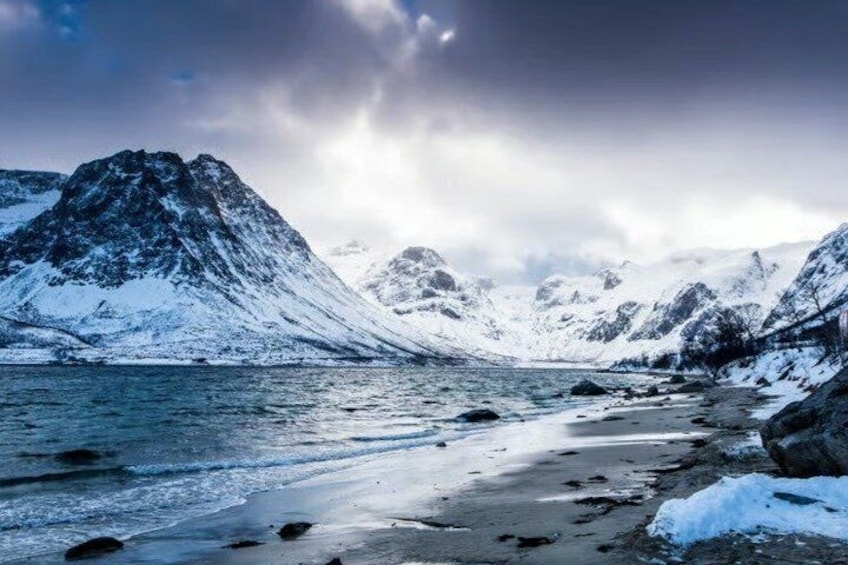 A snowy mountain landscape with a frozen lake and rocky shores. 3