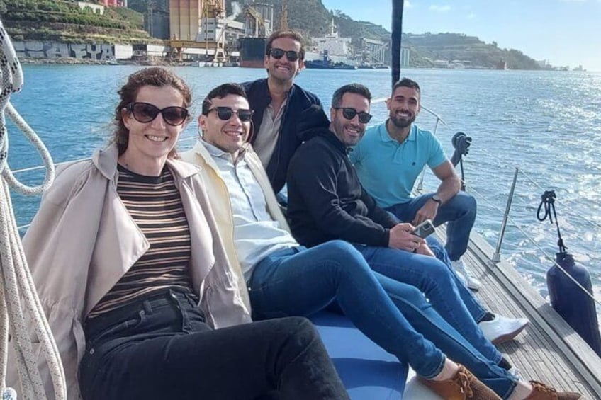 A group of people on a boat with a body of water and buildings in the background. 2