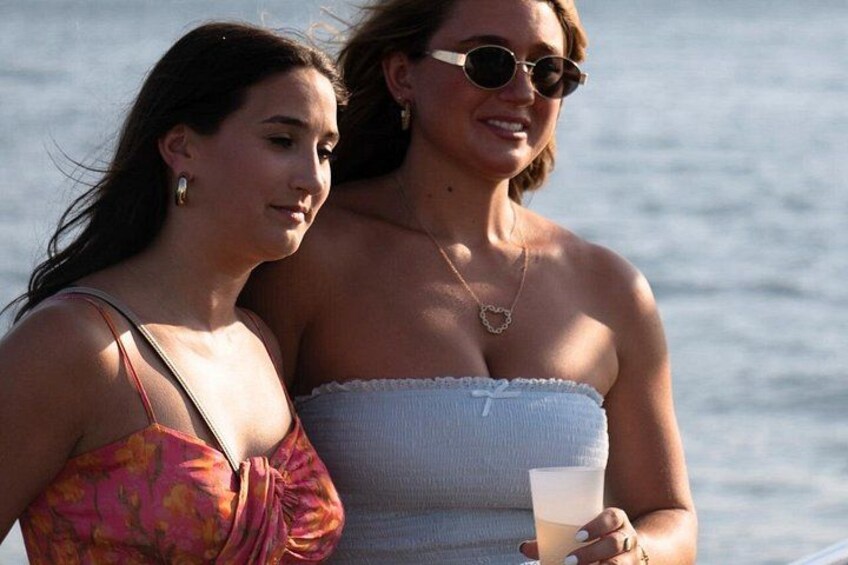 Two people standing by a body of water, one holding a drink. 5
