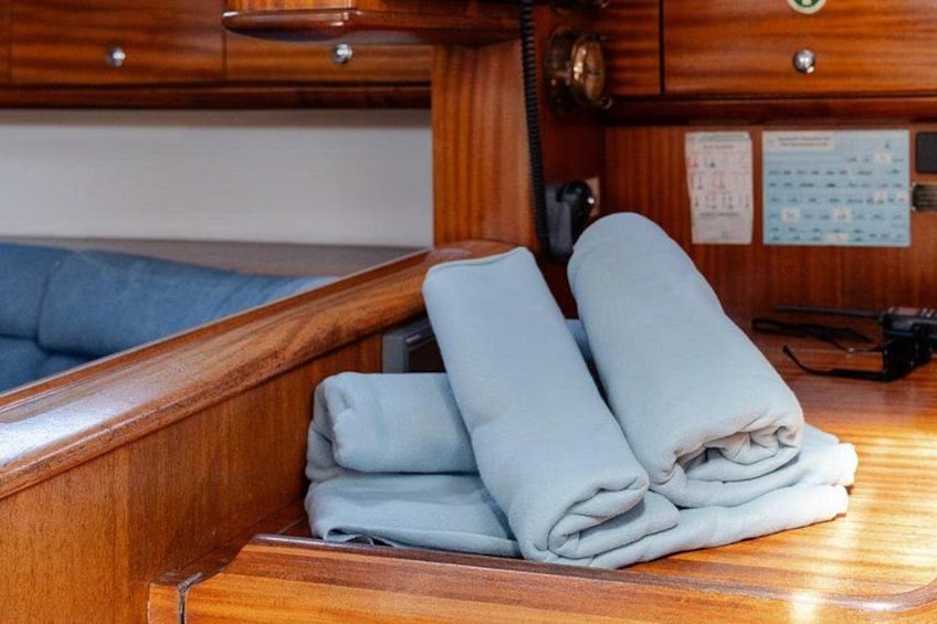 A wooden interior with a bed, a telephone, and folded towels. 3