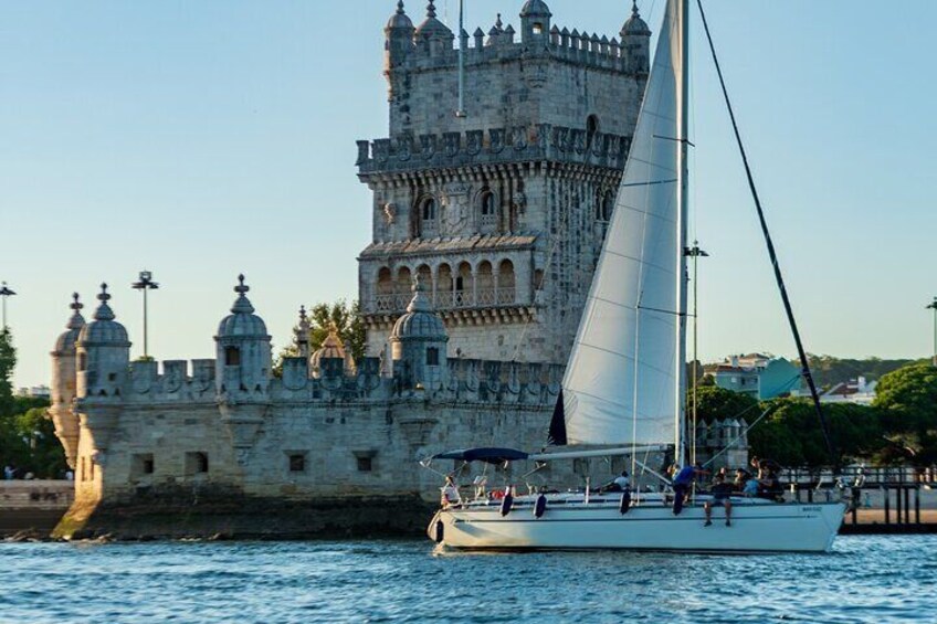 A sailboat with people on board, a castle in the background, and a clear sky. 2