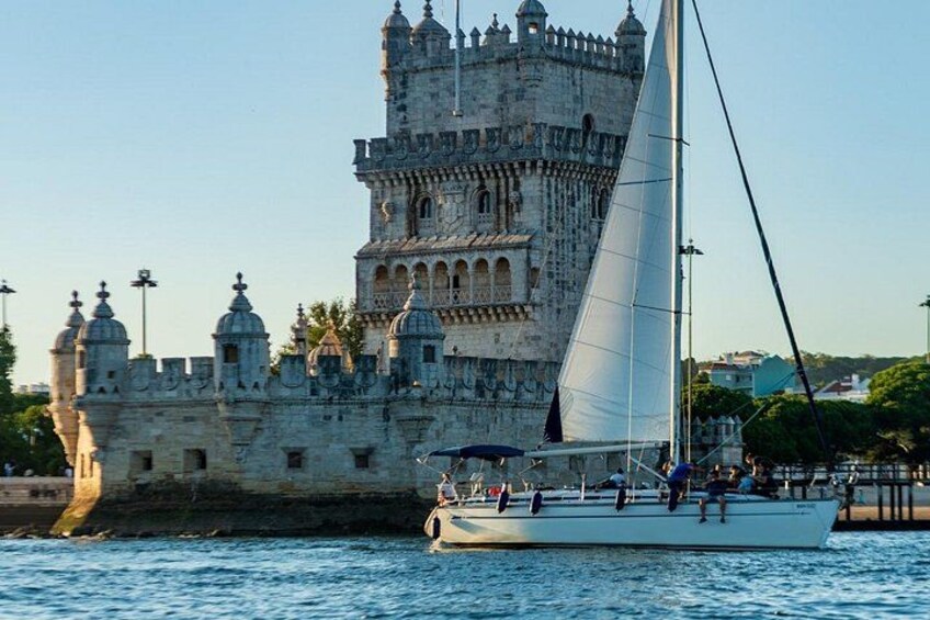 A sailboat with people on board near a historic castle by the water. 3