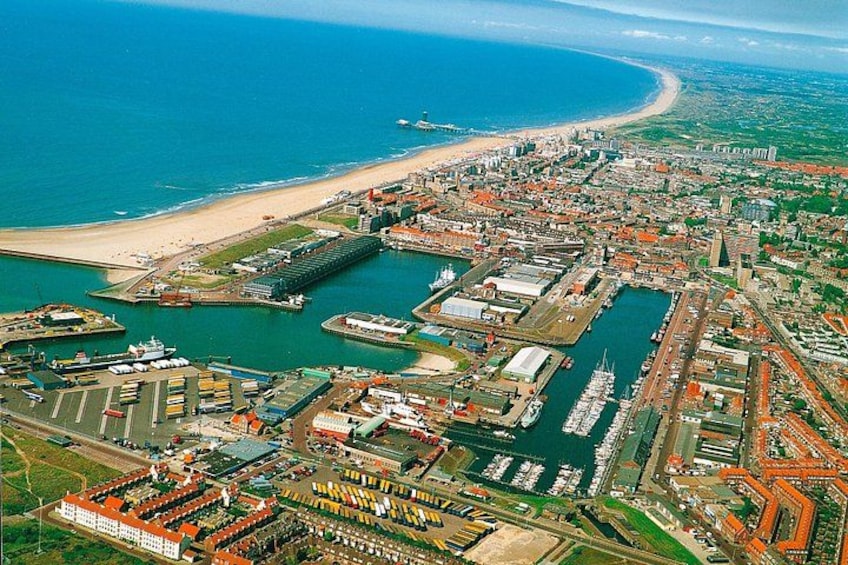 An aerial view of a coastal city with a marina, a beach, and industrial buildings. 4