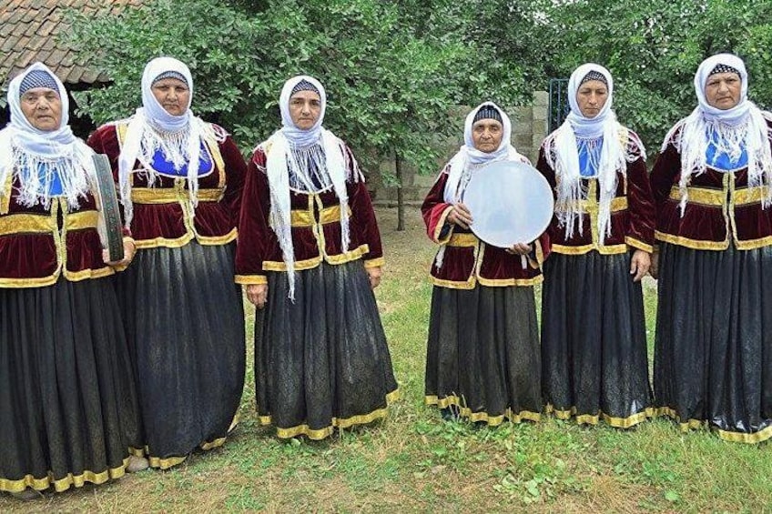 A group of people in traditional attire standing outdoors. 2