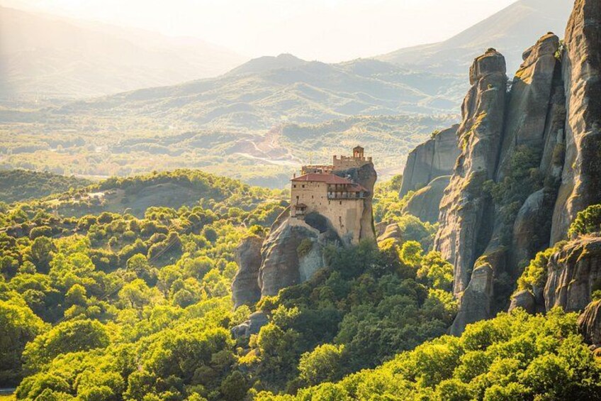 A monastery perched atop a rocky cliff surrounded by lush greenery. 1