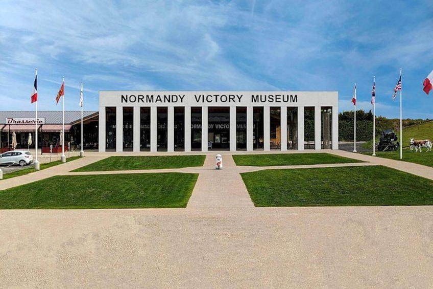 El Museo del Día D en Normandía, con una entrada despejada, banderas y un césped bien cuidado. 1