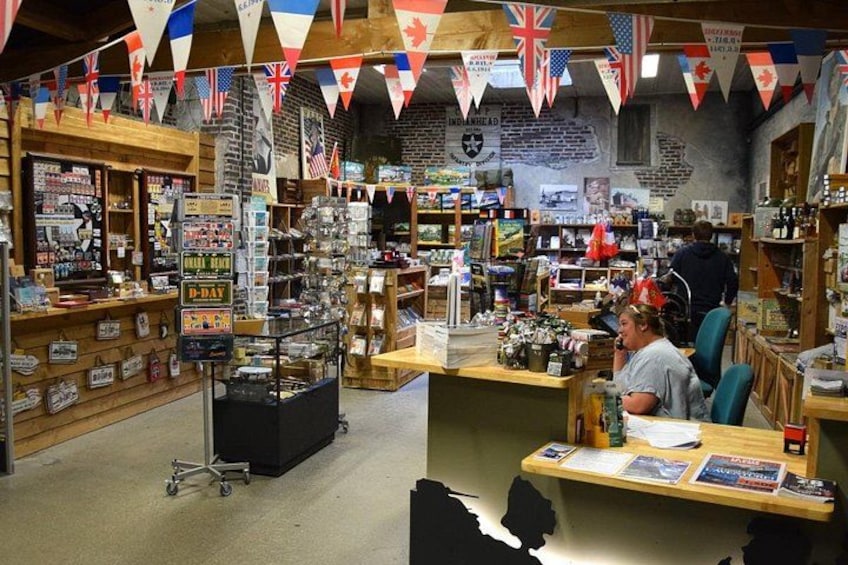 Tienda con diversos artículos en estantes y un mostrador donde se sienta una persona. 2