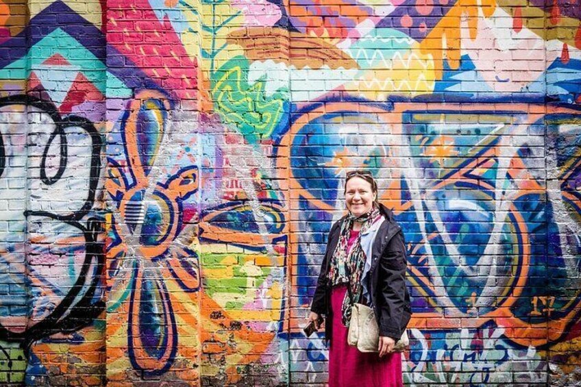 A person standing in front of a colorful graffiti wall. 5