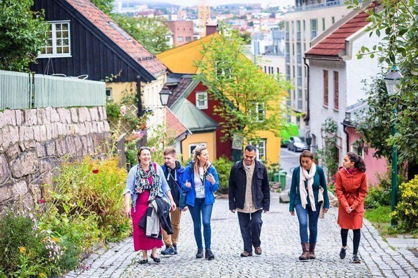 A cobblestone street lined with colorful buildings, a stone wall, and greenery. 1