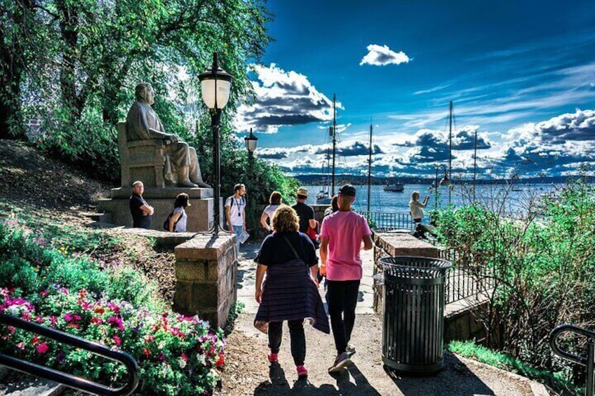 A statue, people walking, and a waterfront. 1