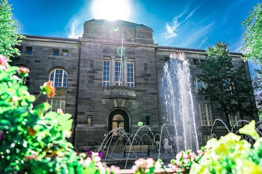 A historic building with a fountain in front, surrounded by greenery. 4