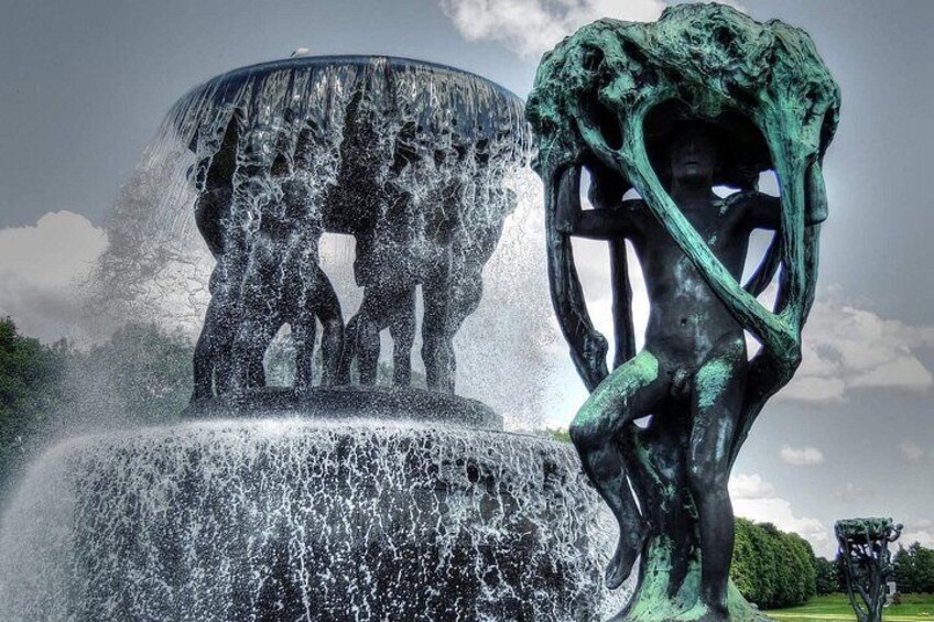 Une sculpture agrémentée d’une fontaine, d’un arbre et d’un ciel nuageux. 5