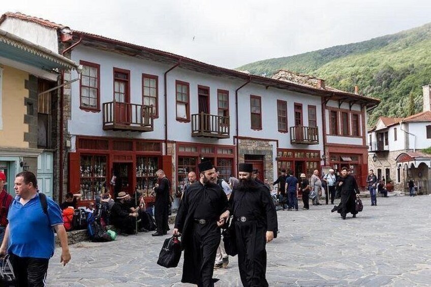 A historical square with traditional buildings, people walking, and a market area. 2