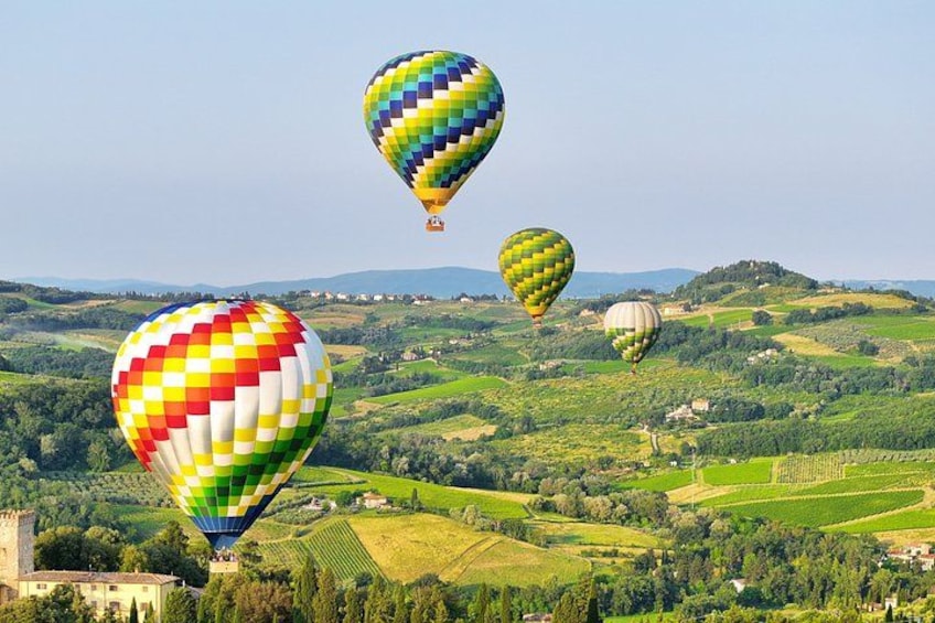 Mongolfiere su un paesaggio collinare con campi e un castello. 1