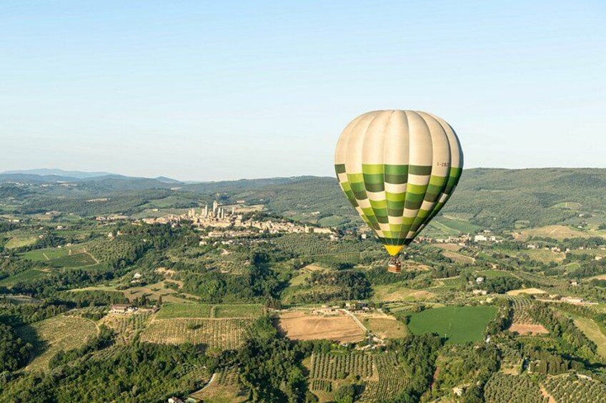 Un globo aerostático sobre un paisaje rural con campos, árboles y un castillo lejano. 1