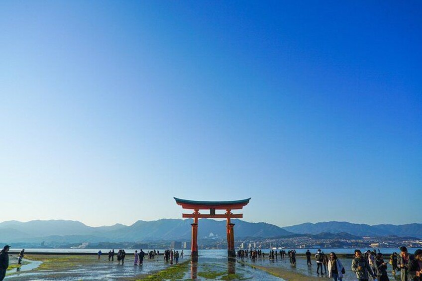 Un torii japonés tradicional con un cielo azul despejado y montañas al fondo. 4
