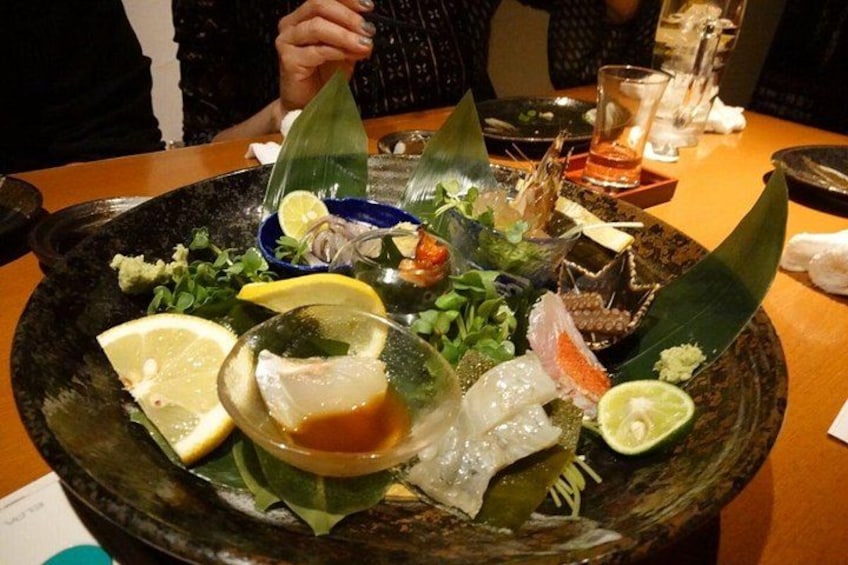 En maträtt med skaldjur och olika ingredienser, serverad på en svart tallrik. 3
