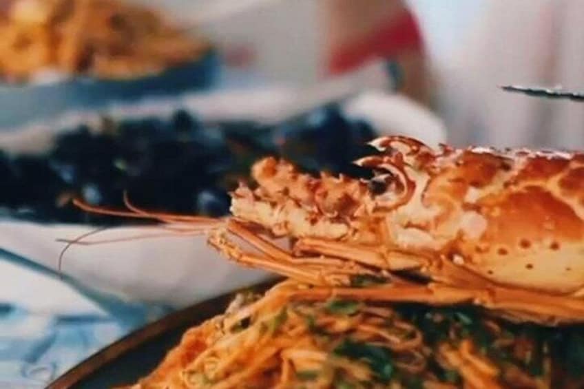 A plate of pasta with a cooked lobster on top. 2