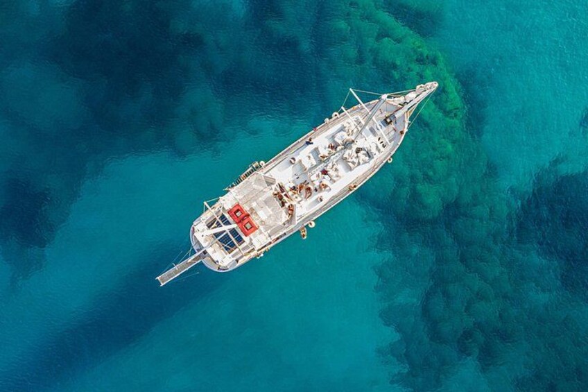 Een boot op turkoois water, met helder zicht tot op de zeebodem. 1