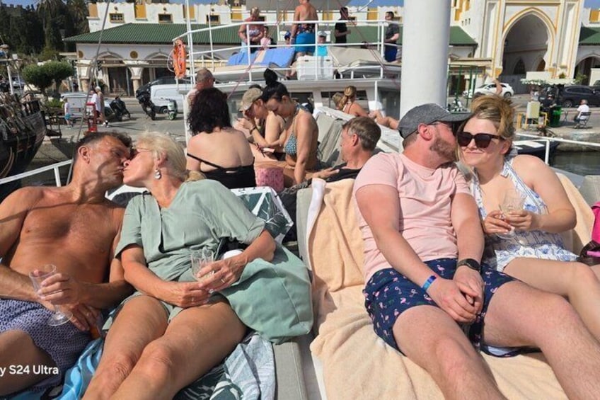 People relaxing on a boat with a marina and buildings in the background. 5