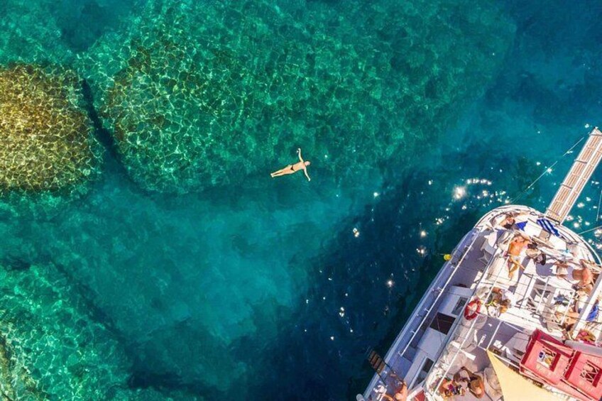 A clear blue sea with a boat and a person swimming. 4