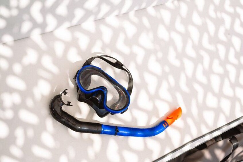Een snorkelmasker en snorkel op een wit oppervlak met schaduwpatronen. 2