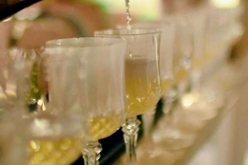 Glasses being filled with a yellow liquid, likely a beverage. 4