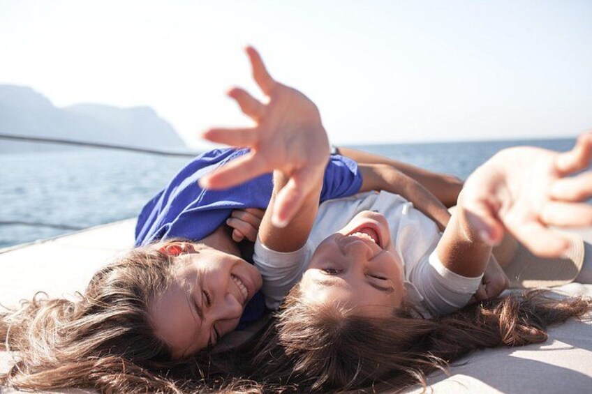 Two people lying on a beach with a body of water and mountains in the background. 3