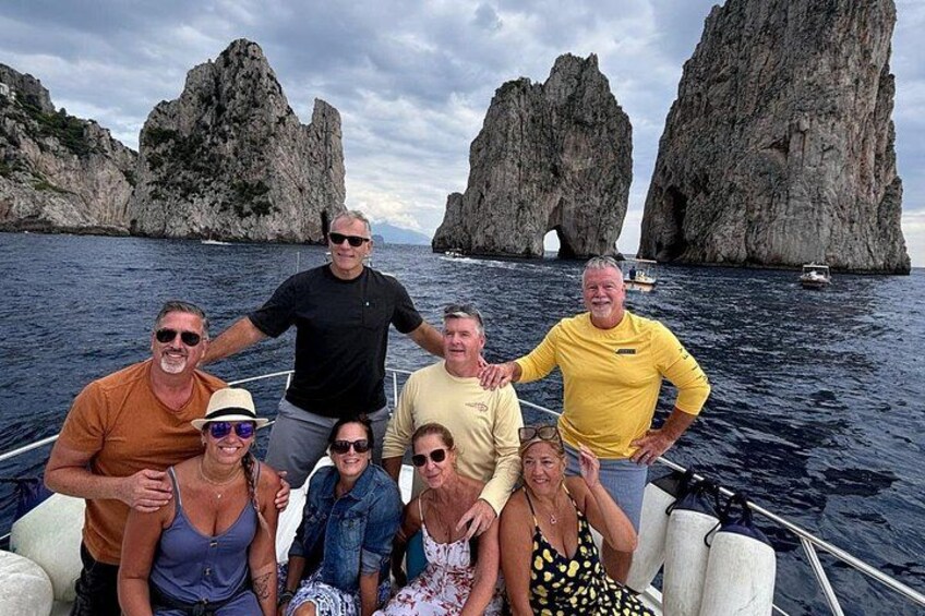 A group of people on a boat with rocky cliffs in the background. 2
