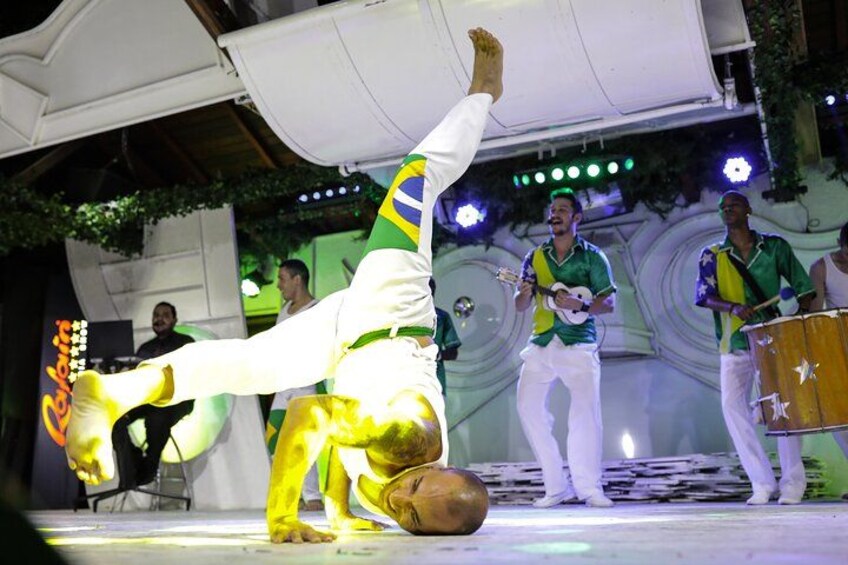 A person performing a handstand with a drum in a festive setting. 5
