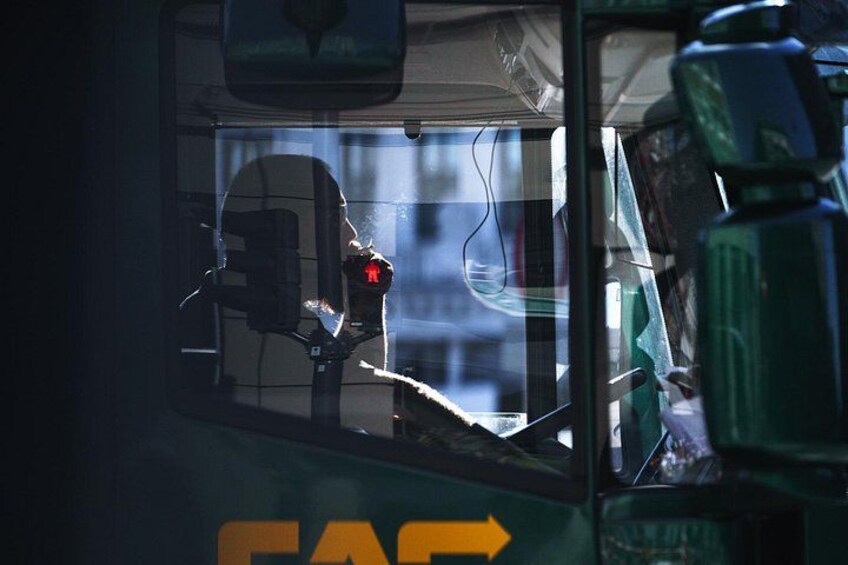 A bus interior with a window, a rearview mirror, and a green object on the right. 5