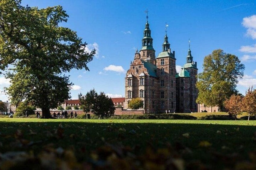 A historic building with multiple spires and a large tree in the foreground. 3