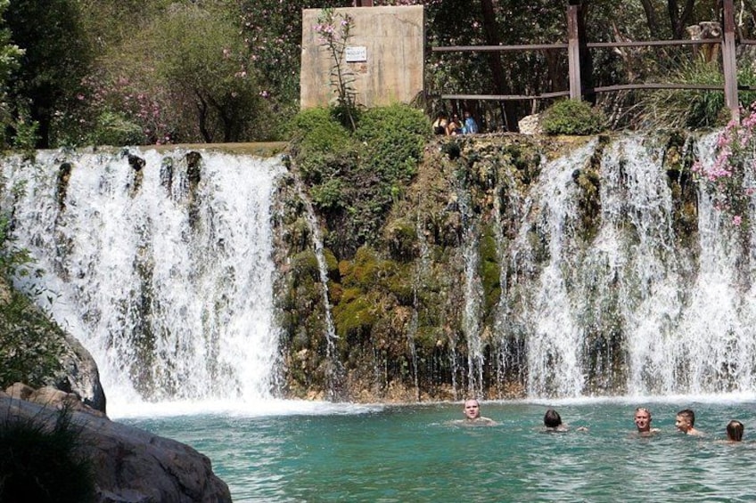 A waterfall cascading into a pool with people swimming. 4
