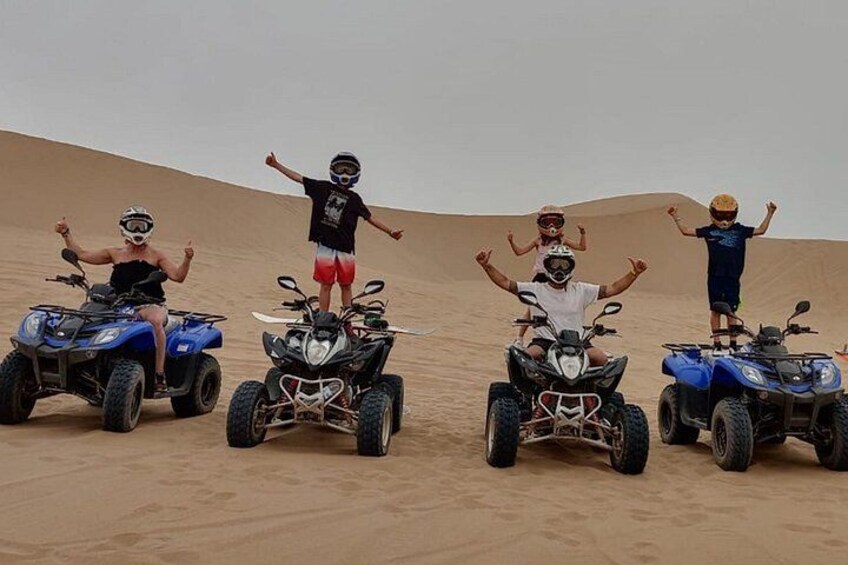 Quattro persone su veicoli fuoristrada in un deserto con dune di sabbia. 2