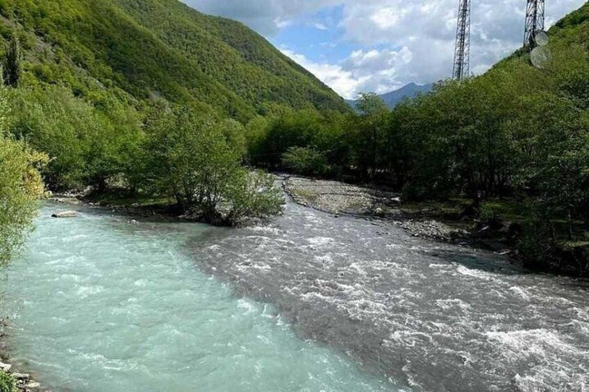 Un río serpentea por un valle con abundante vegetación y una montaña al fondo. 5