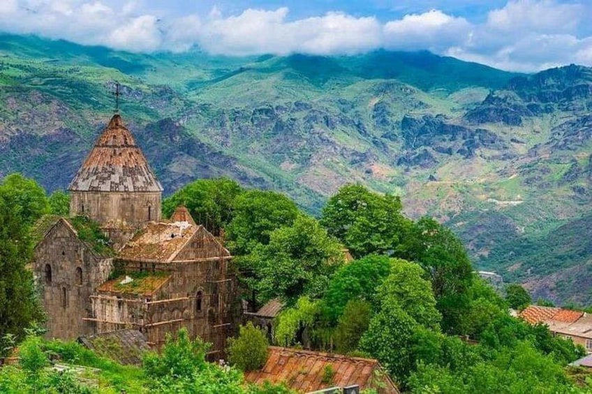 A historic church surrounded by lush greenery and mountains. 3