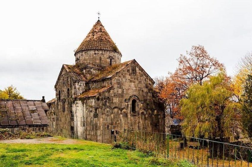 A stone church with a conical roof, surrounded by autumn-colored trees. 4