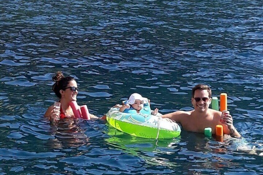 Drei Personen treiben im Wasser mit einem Schwimmreifen, während sie Auftriebshilfen halten. 2