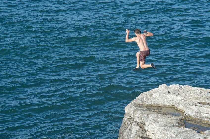 A person jumping off a rocky cliff into the water. 5